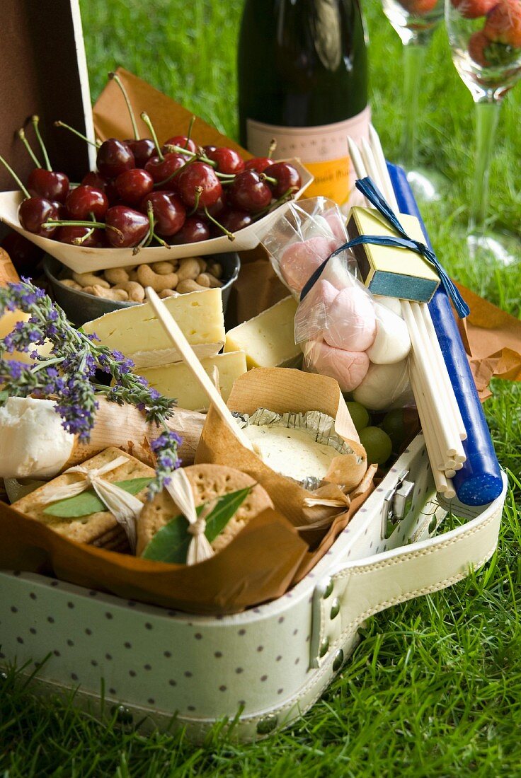 A picnic hamper with cheese, crackers, marshmallows, cashew nuts and cherries