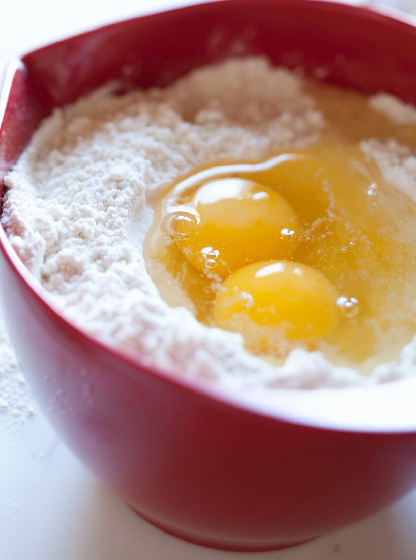 Aufgeschlagene Eier in einer Schüssel Mehl
