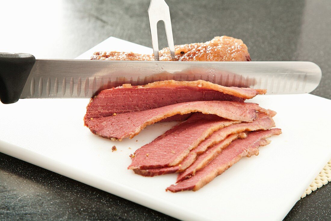 Slicing Corned Beef on a White Plastic Cutting Board