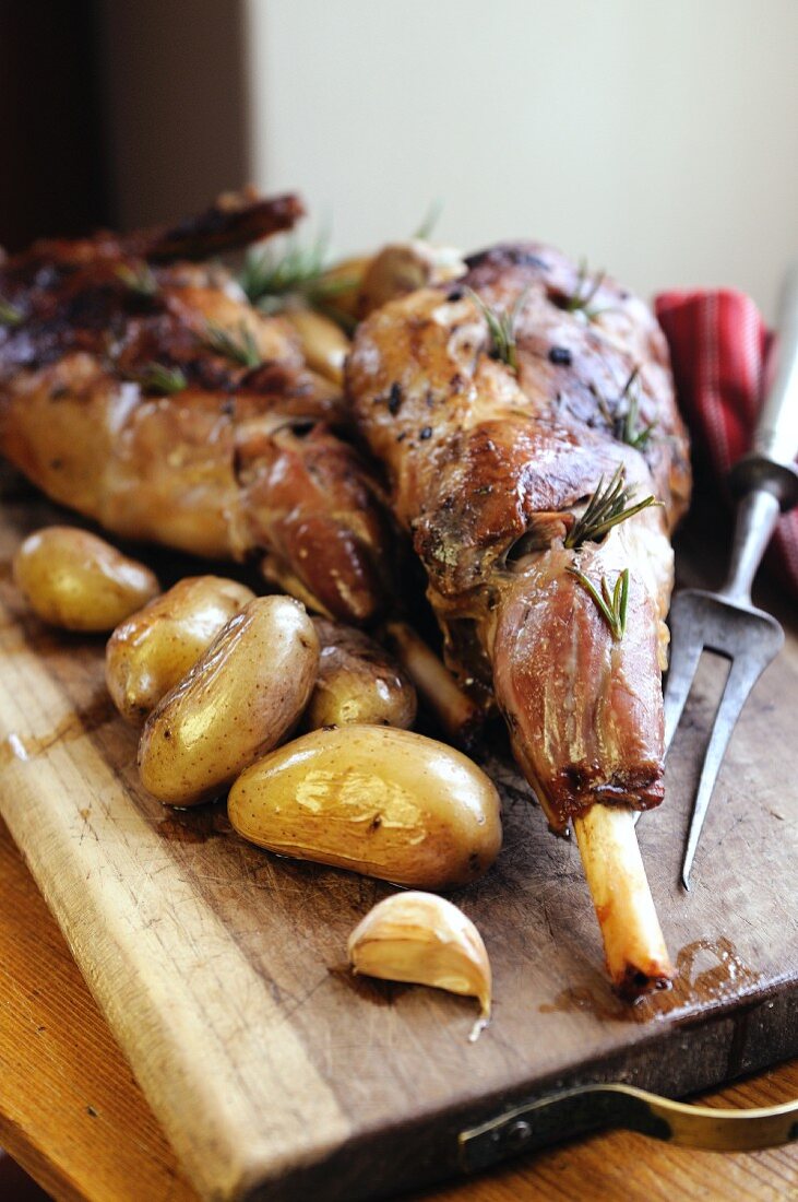 Legs of lamb with roast potatoes on a wooden board
