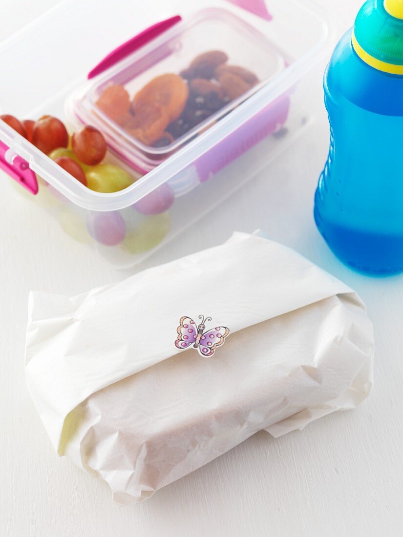 A wrapped sandwich, a lunchbox and a bottle of water