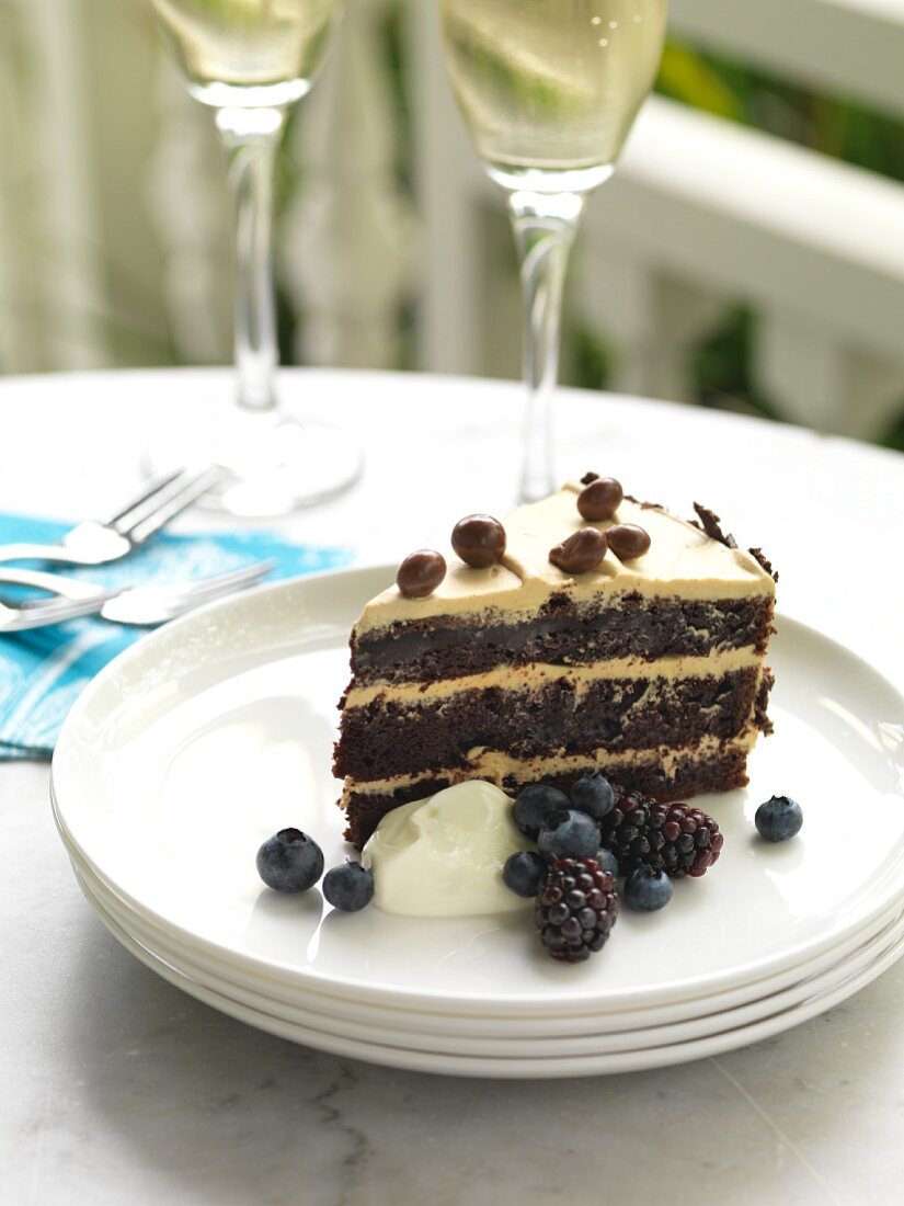 A slice of chocolate and coffee cake with berries and cream