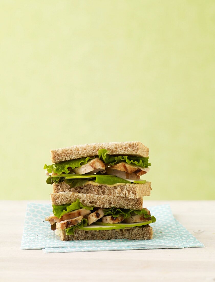 Grilled Chicken Sandwich with Lettuce and Apple Slices on Wheat Bread; Halved and Stacked