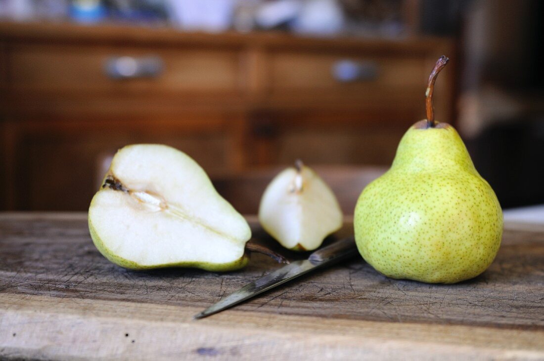Williams pears, whole and halved, on a wooden board