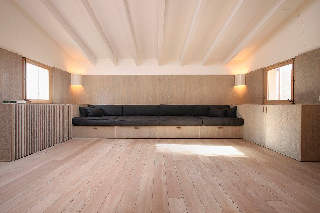 Dielenboden und eingebaute Sitzbank aus Holz mit schwarzen Sitzpolstern im minimalistischen Wohnraum