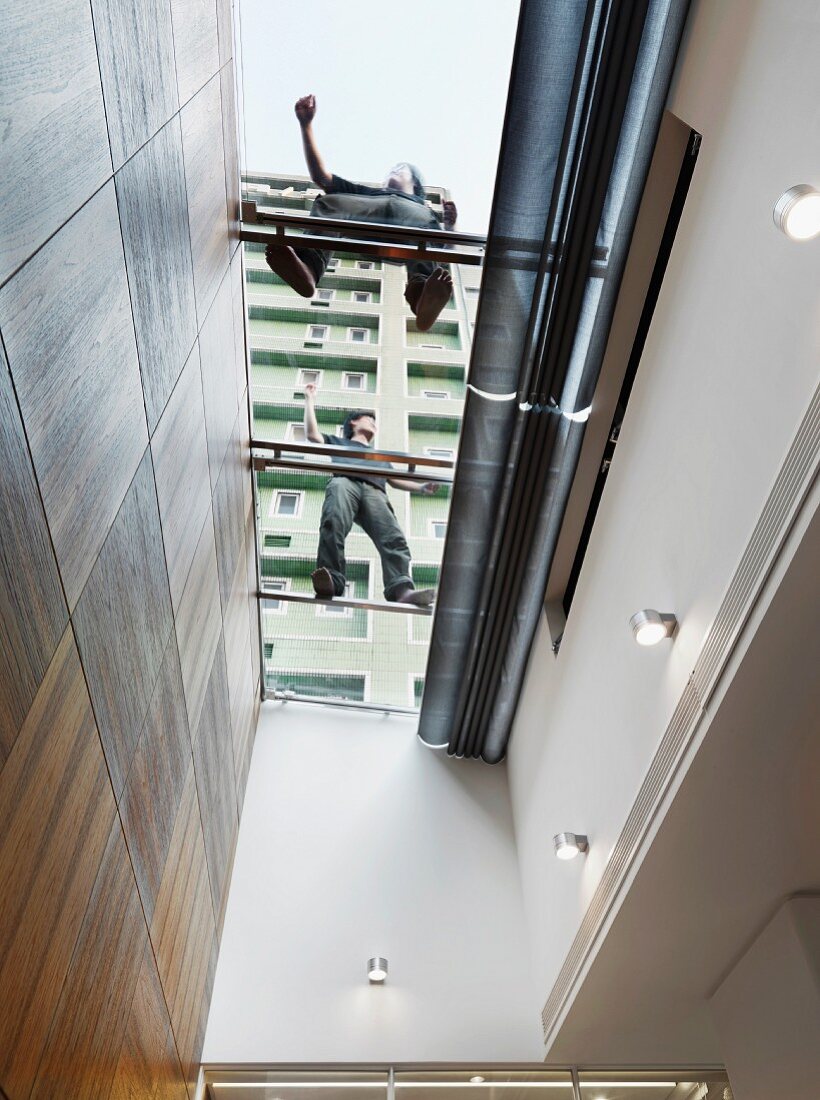 Two people on glass roof above light well