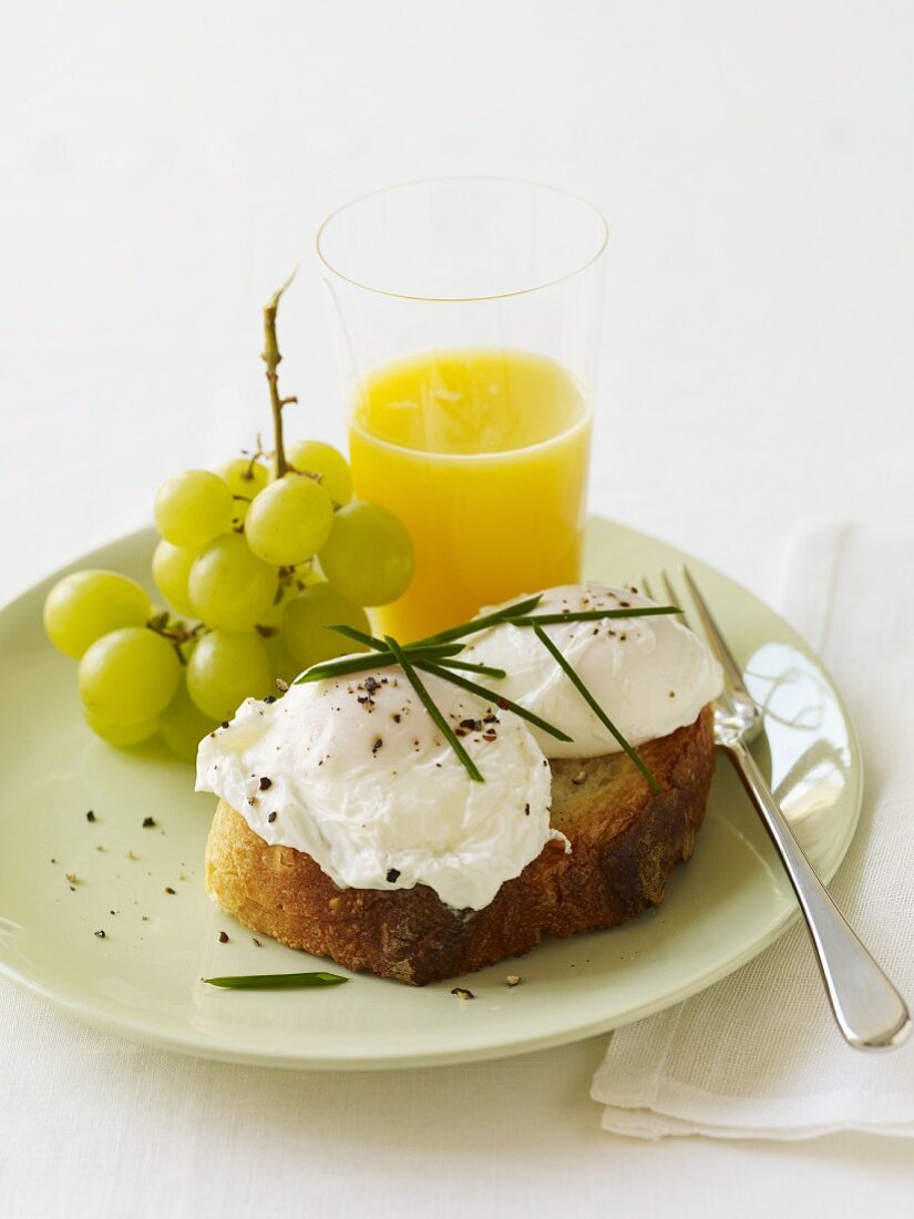 Pochierte Eier auf Röstbrot mit Trauben und Orangensaft