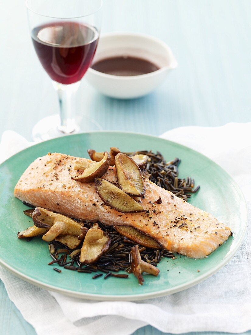 Salmon Fillet with Mushrooms Over Wild Rice; Glass of Wine and Bowl of Sauce