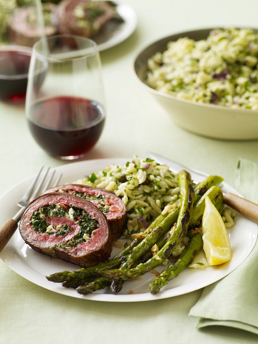 Slices of Stuffed Rolled Beef Served with Asparagus and Rice; Red Wine