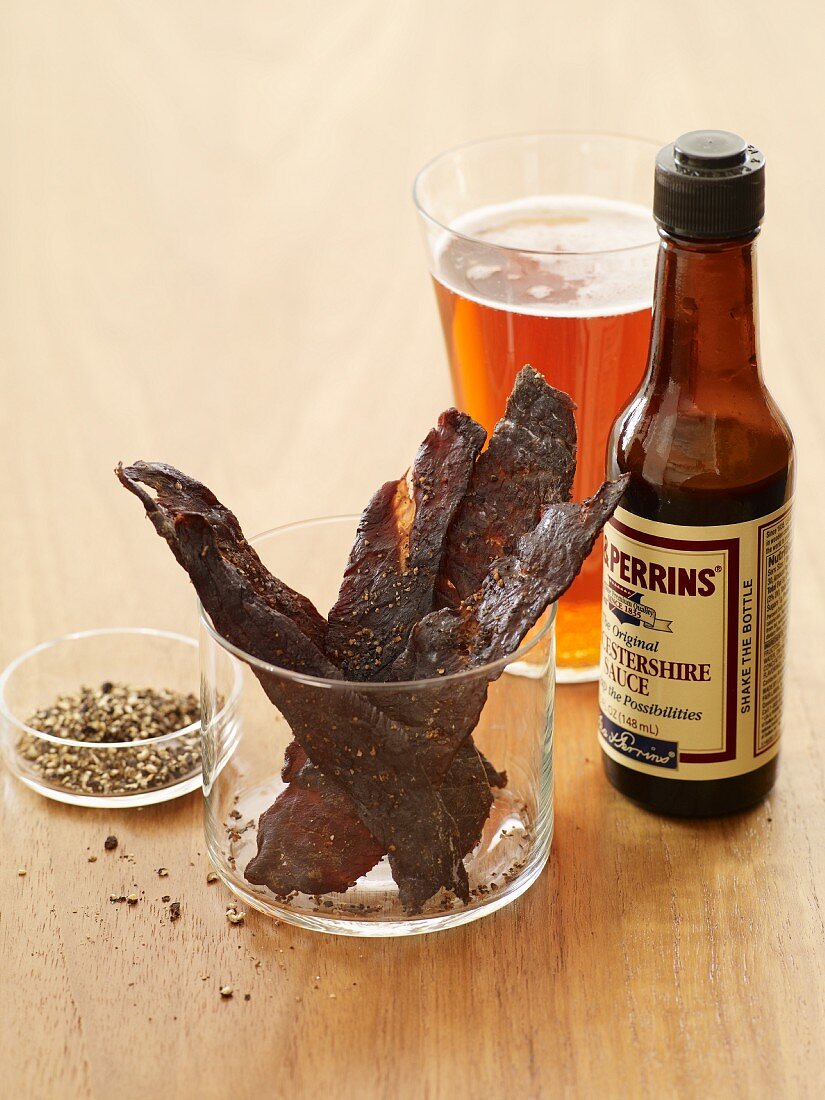 Beef Jerky with a Bottle of Worcestershire Sauce, Glass of Beer and Cracked Pepper