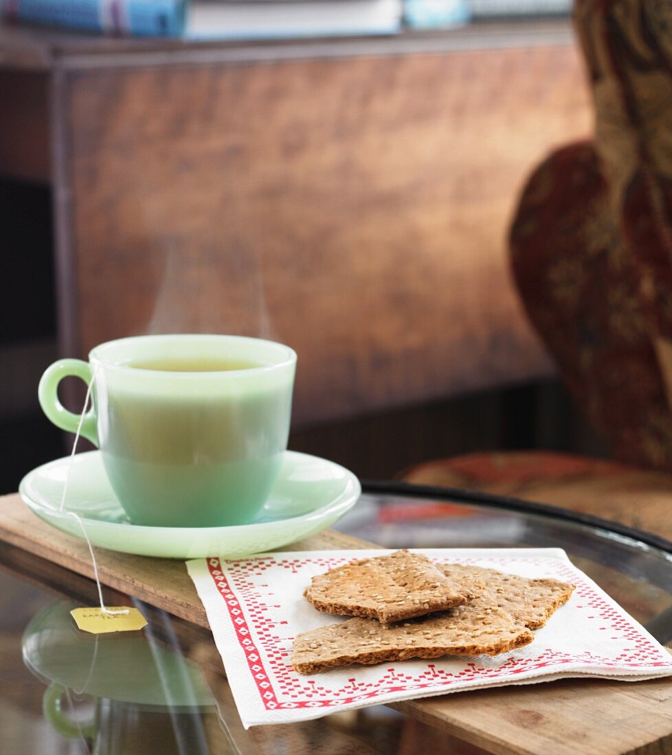 Eine Tasse heißer Tee mit Sesamcrakern auf Serviette