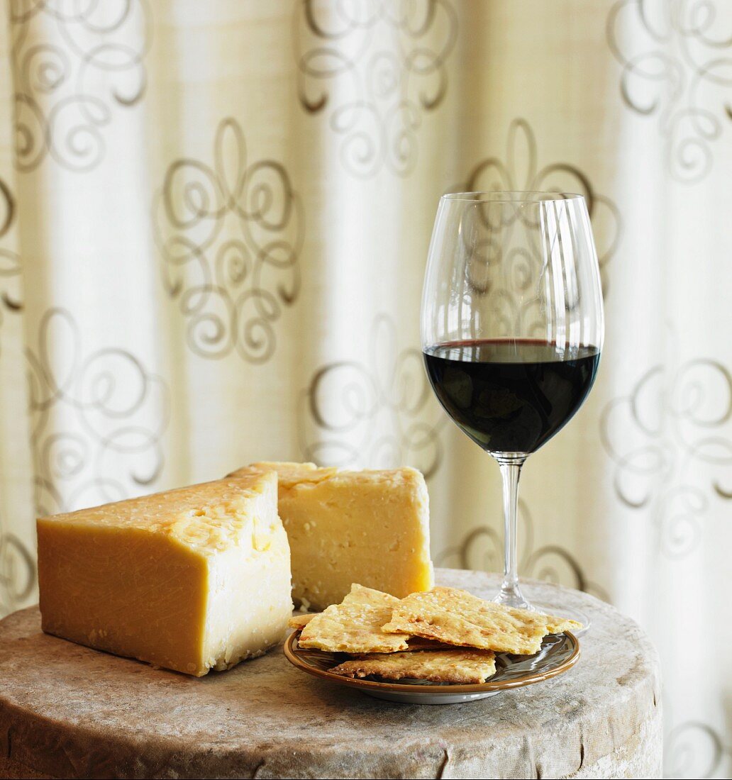 Stillleben mit Cheddarkäse, Glas Rotwein & Crackern