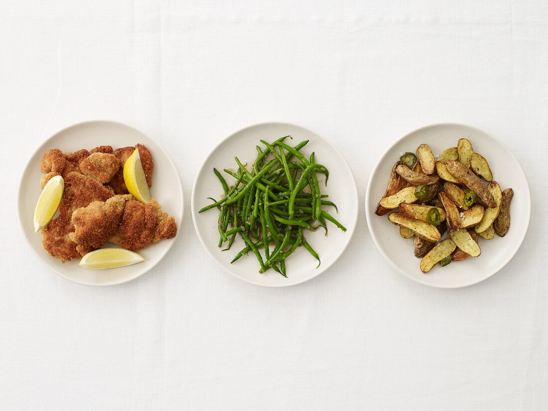 Panierte Hühnerbrust, grüne Bohnen & Kartoffeln auf drei Tellern