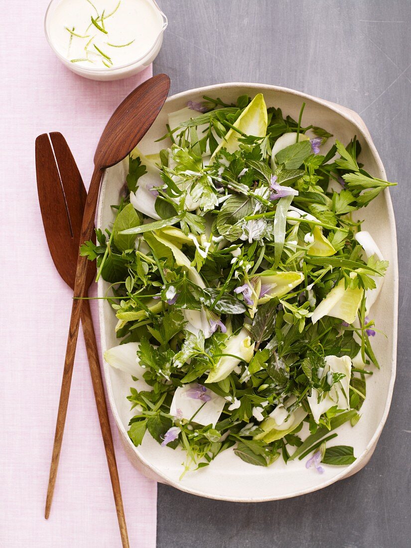 Herb Salad in a Serving Dish with Wooden Servers and Creamy Dressing; From Above