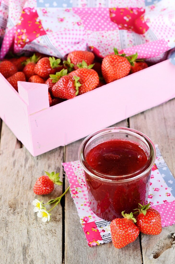 A jar of strawberry jam and fresh strawberries