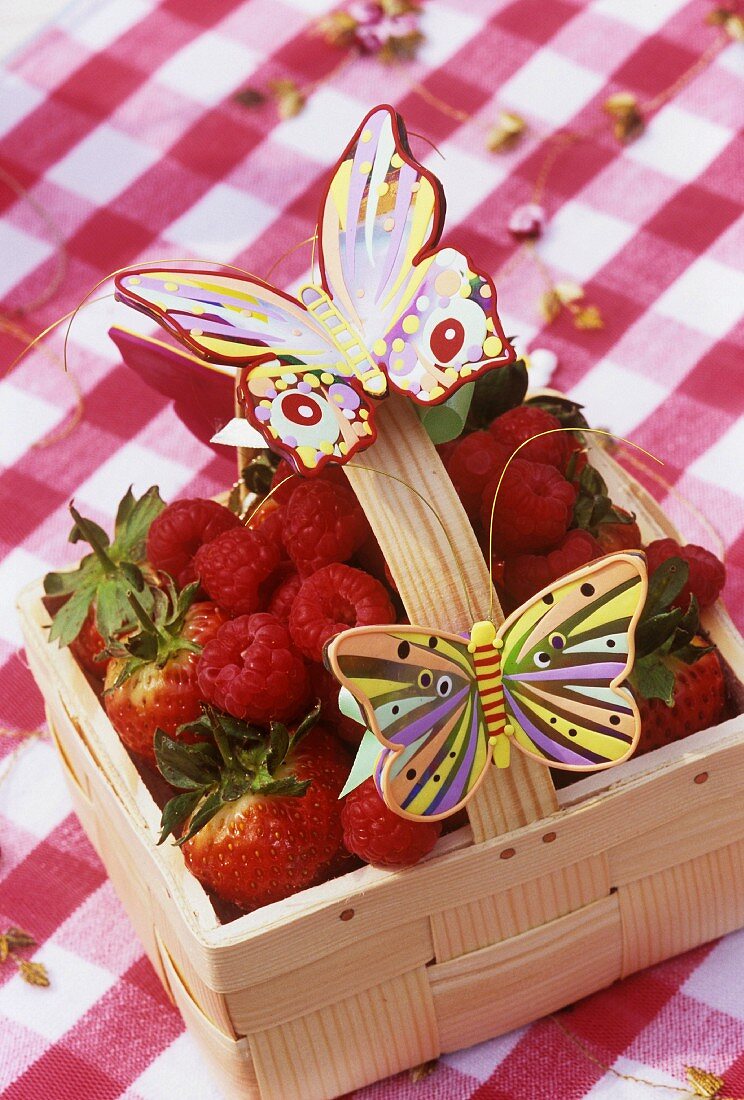 Modelling clay butterflies on punnet of berries