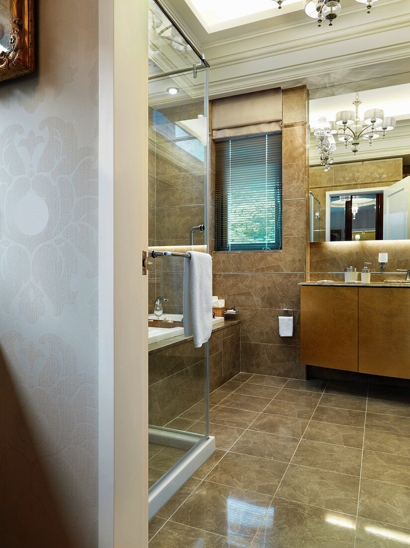 View through an open door into a modern bathroom with light brown flooring and wall tiles