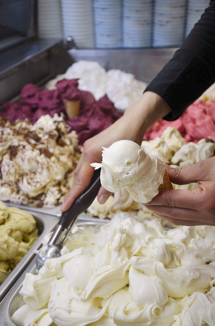 A ice cream seller scooping banana ice cream into a cone