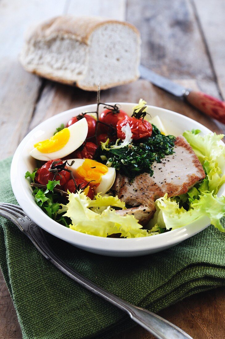 Salad of pan fried tuna steak, boiled egg, roasted vine tomatoes and pesto