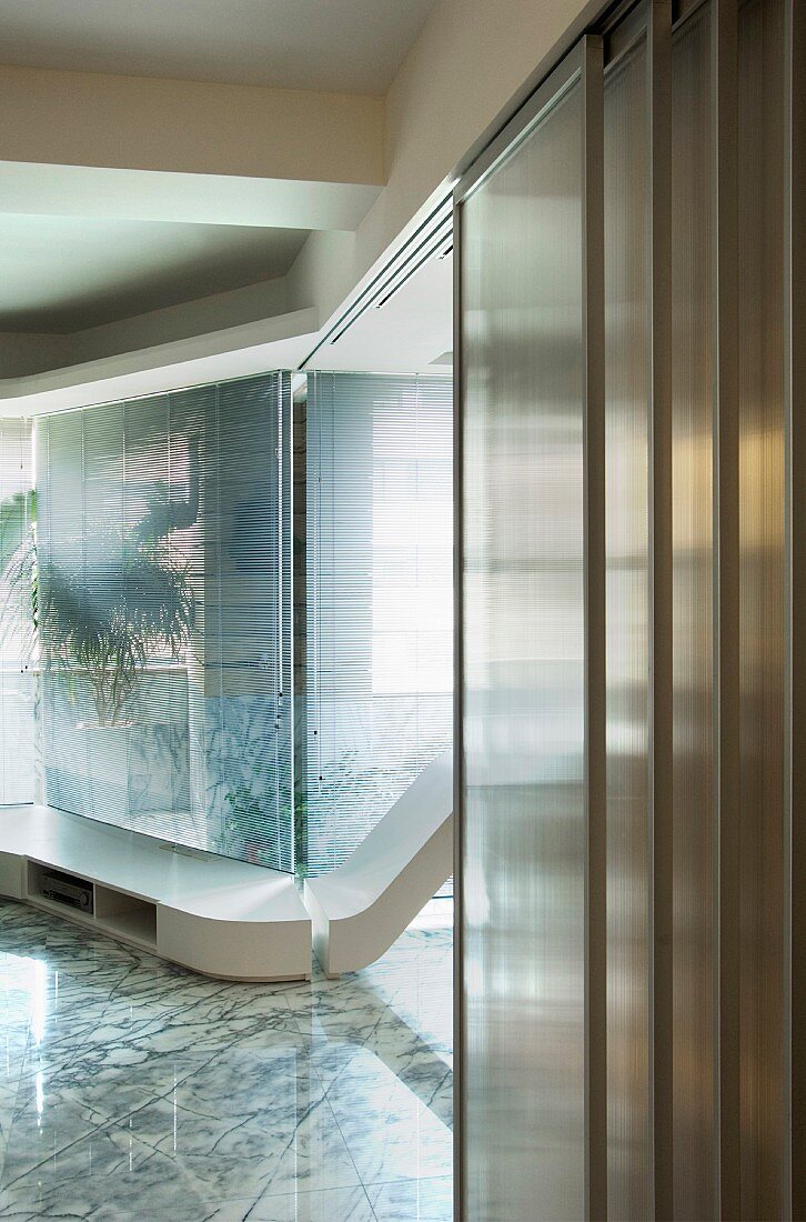 Detail of a contemporary living room with low built-in shelves on a stone floor in front of a window