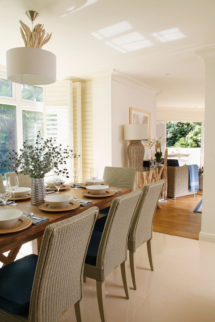 Festively set oak table with modern wicker chairs in open-plan living-dining room