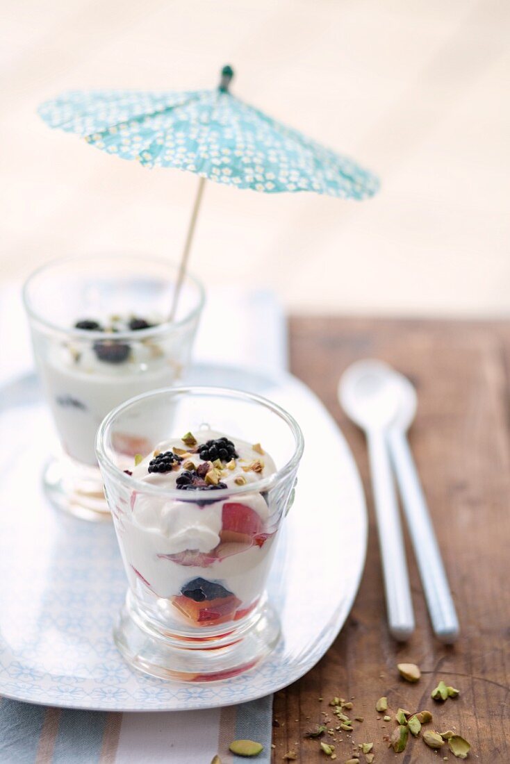 Joghurt mit frischen Früchten in Gläsern mit Cocktailschirmchen