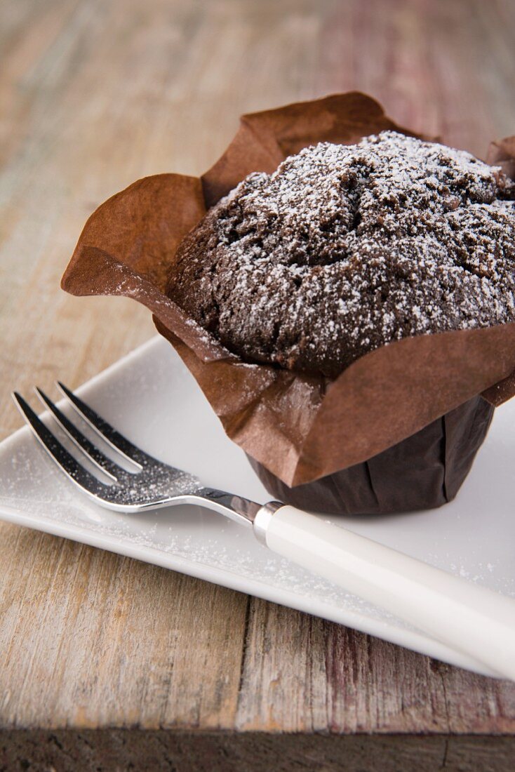 Schokoladenmuffin mit Puderzucker in Papier