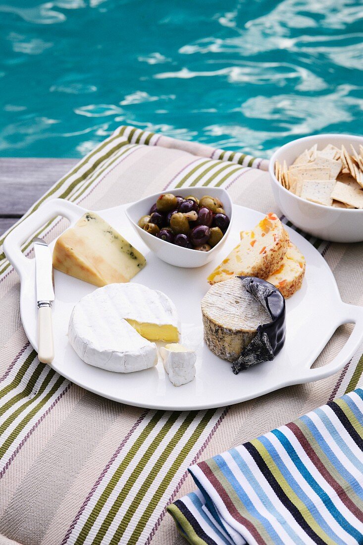 Käseteller mit Oliven und Crackern am Swimmingpool