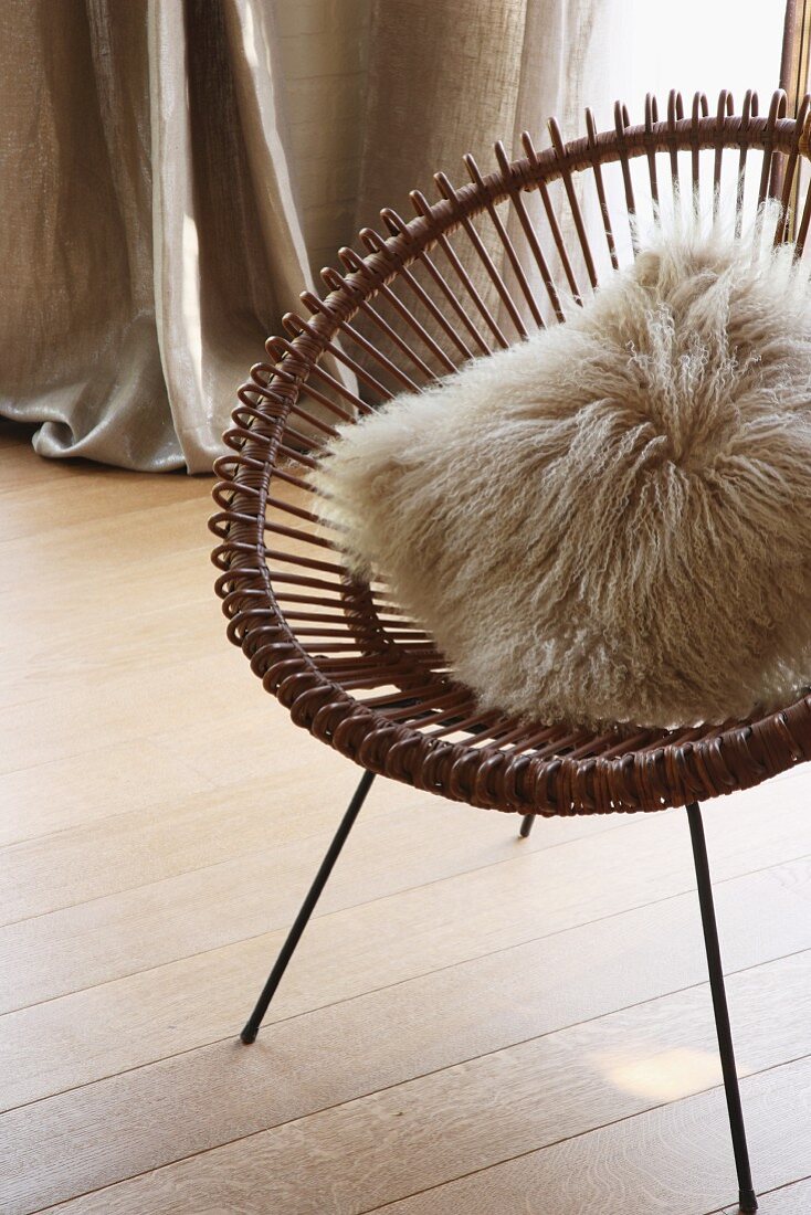 Fur cushion on retro metal chair on wooden floor