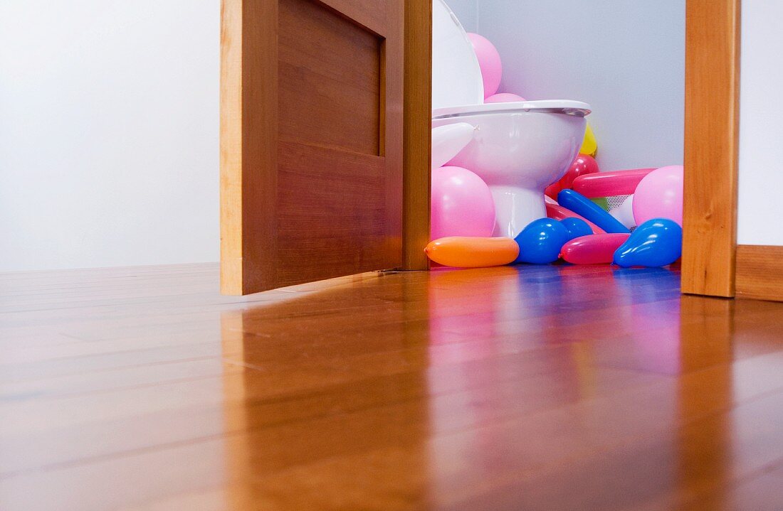 Viele bunte Luftballons in einem Toilettenraum