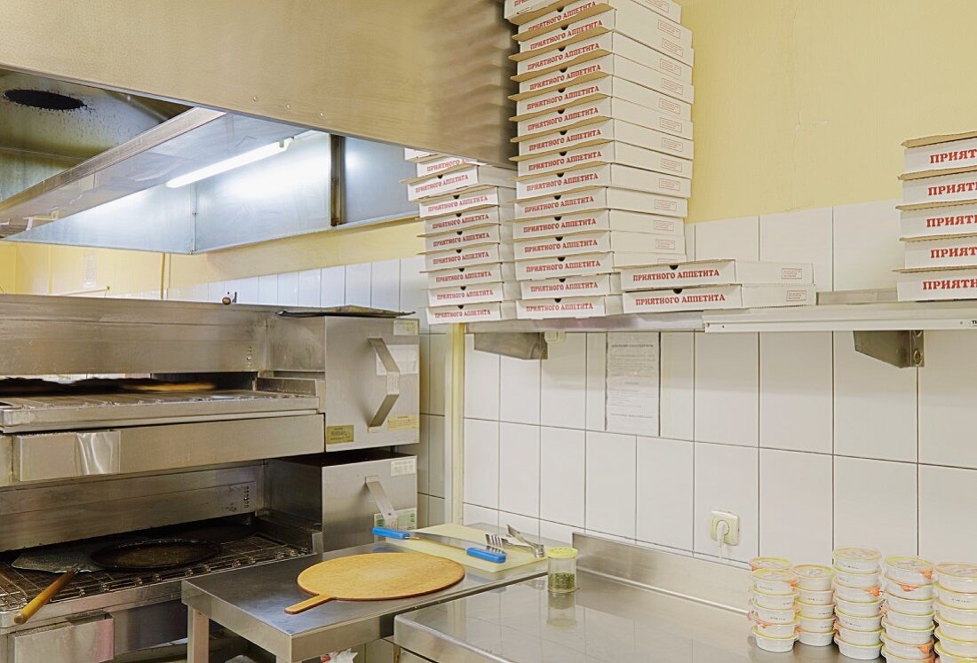 Küche einer Pizzeria mit industriellem Pizzaofen und Pizzakartons