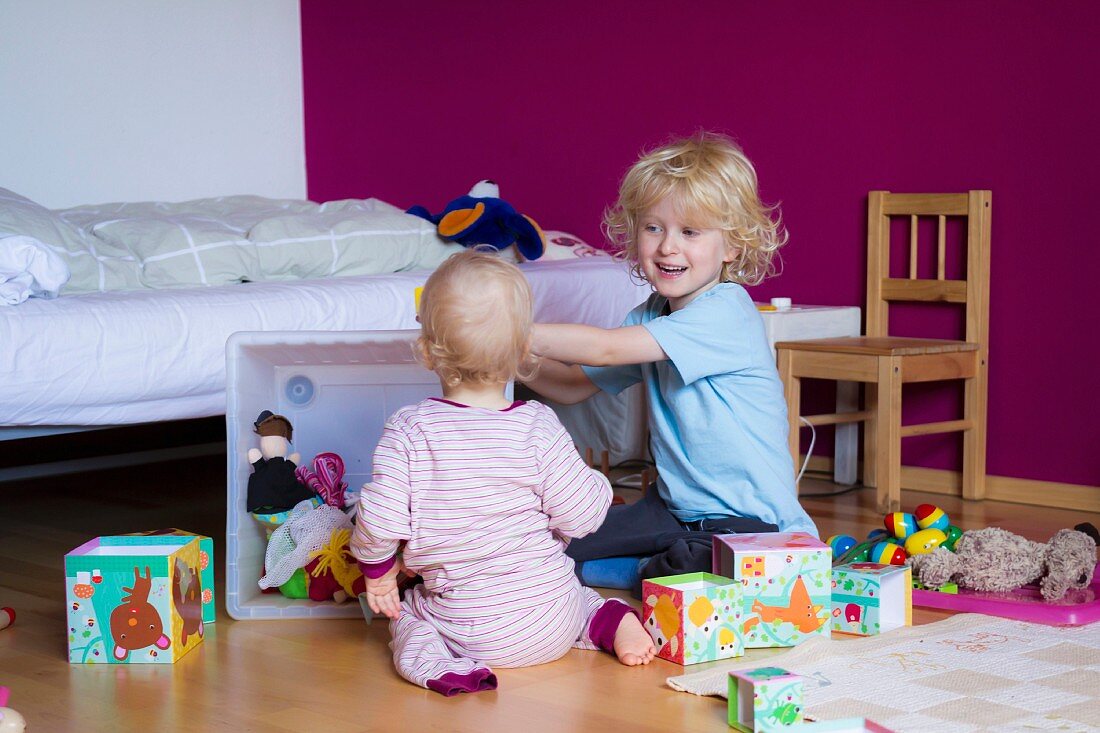 Siblings playing together in bedroom