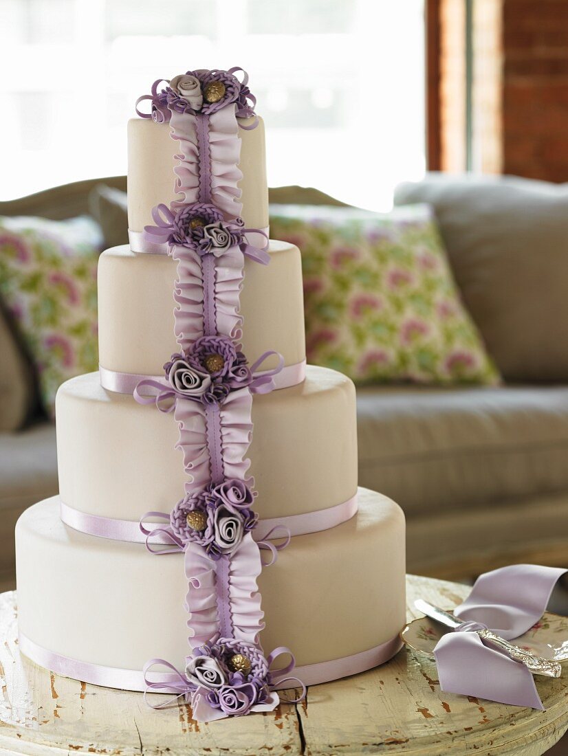 A Four Tier Wedding Cake with Lavender Ribbon and Flowers