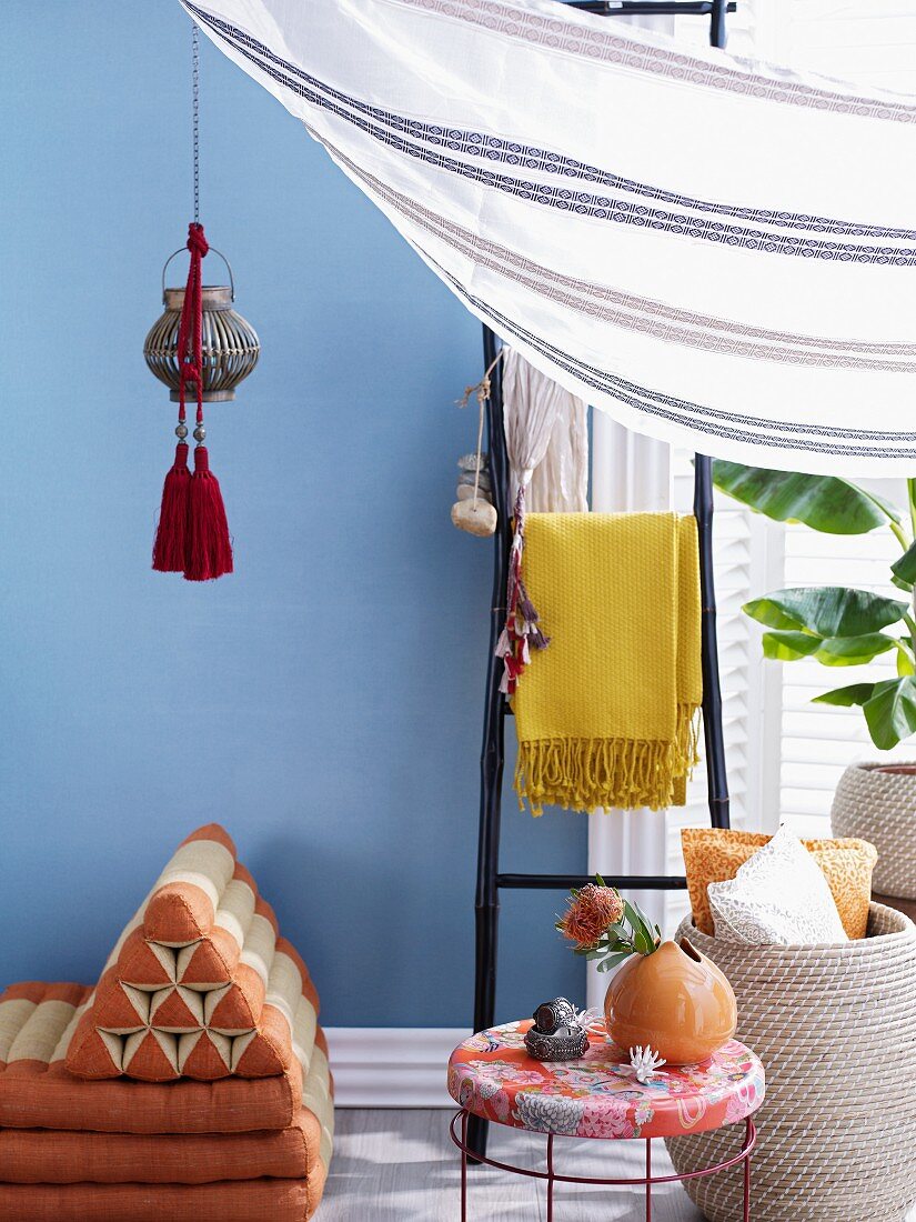 Exotically inspired interior design with lantern and tassels hanging above Thai floor cushions