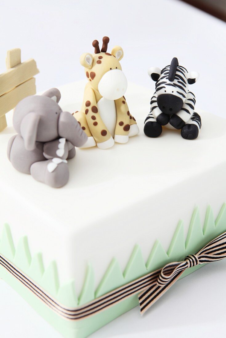 A white cake decorated with animals made from fondant icing