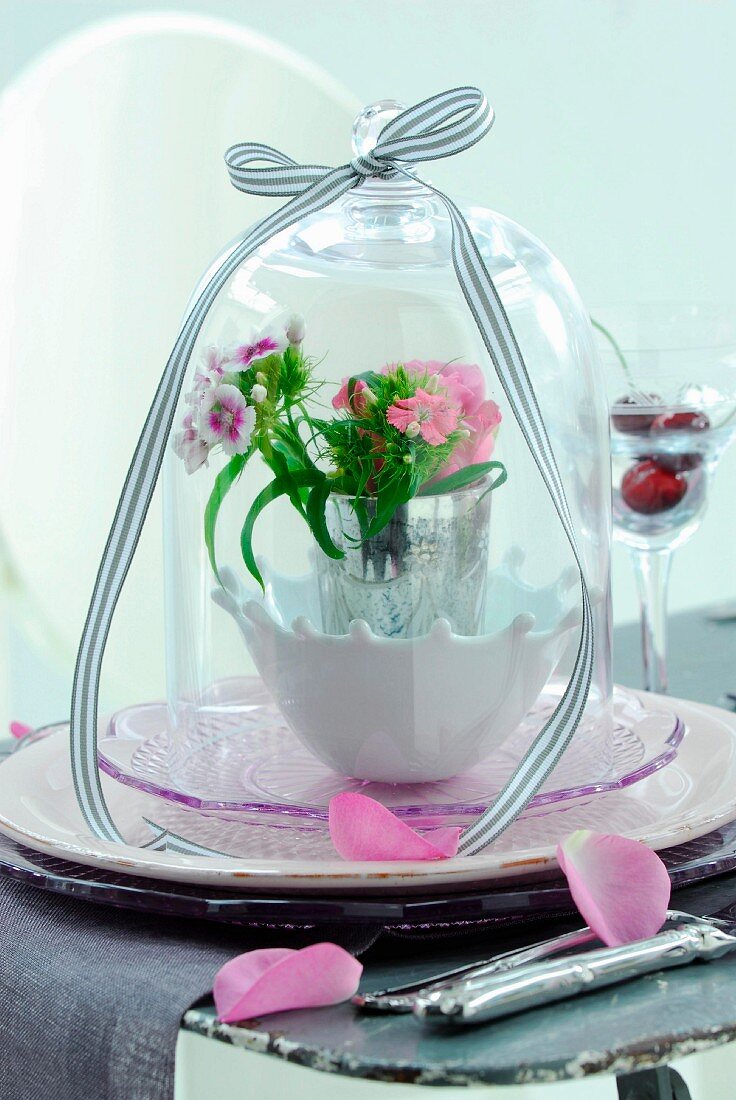 Spring posy in vase on dish under glass cover