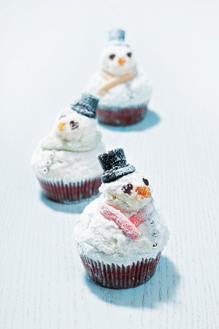 Cupcakes als Schneemänner auf Holzuntergrund