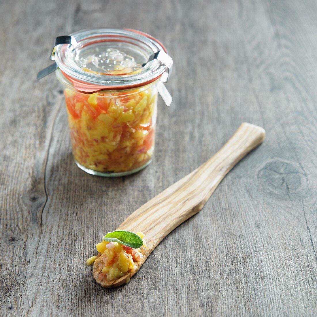 Mango-Salsa im Glas und auf einem Holzlöffel