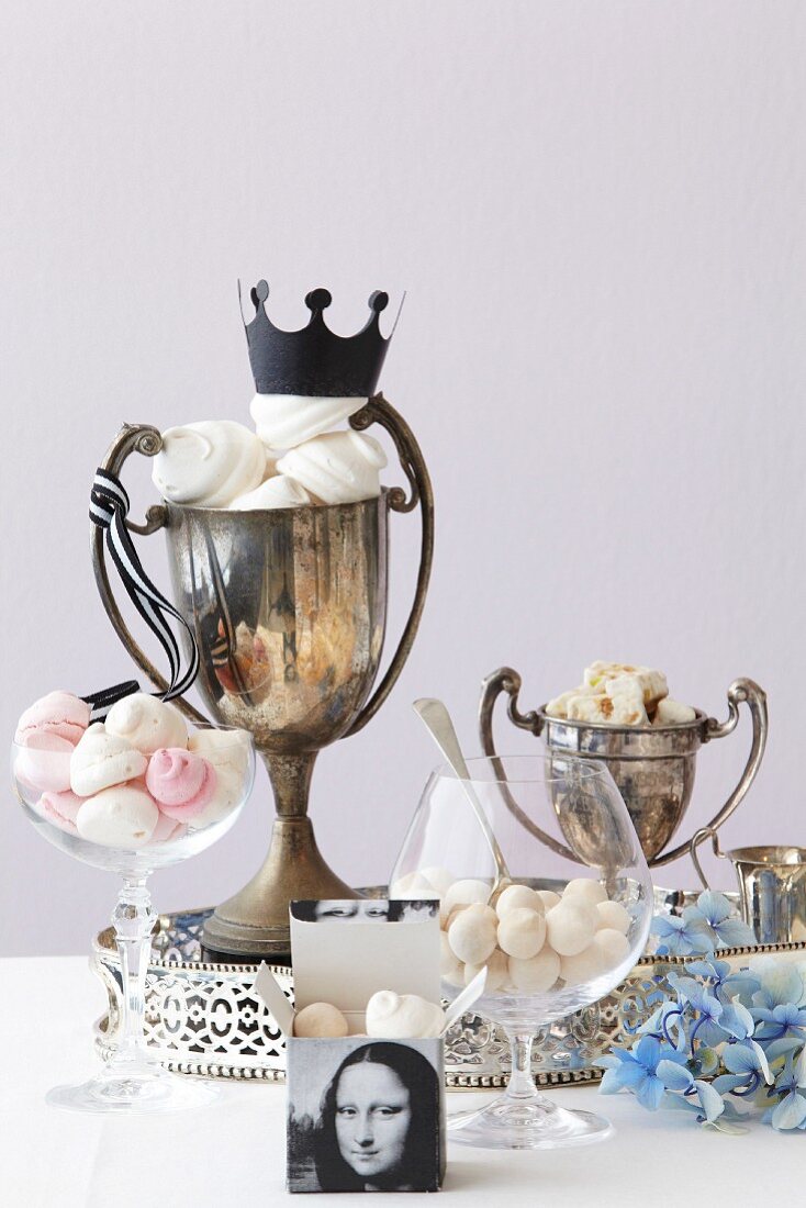 Glasses and old trophies filled with meringues, nougat and pralines