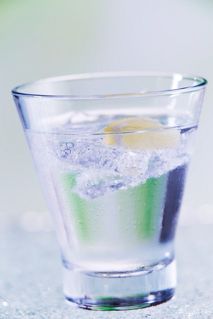 Ein Glas Mineralwasser mit Eiswürfeln und Zitronenscheibe