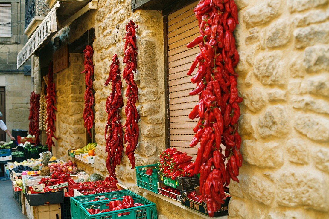 Getrocknete Paprikaschoten hängen an der Wand eines Gemüse-und Obstladens