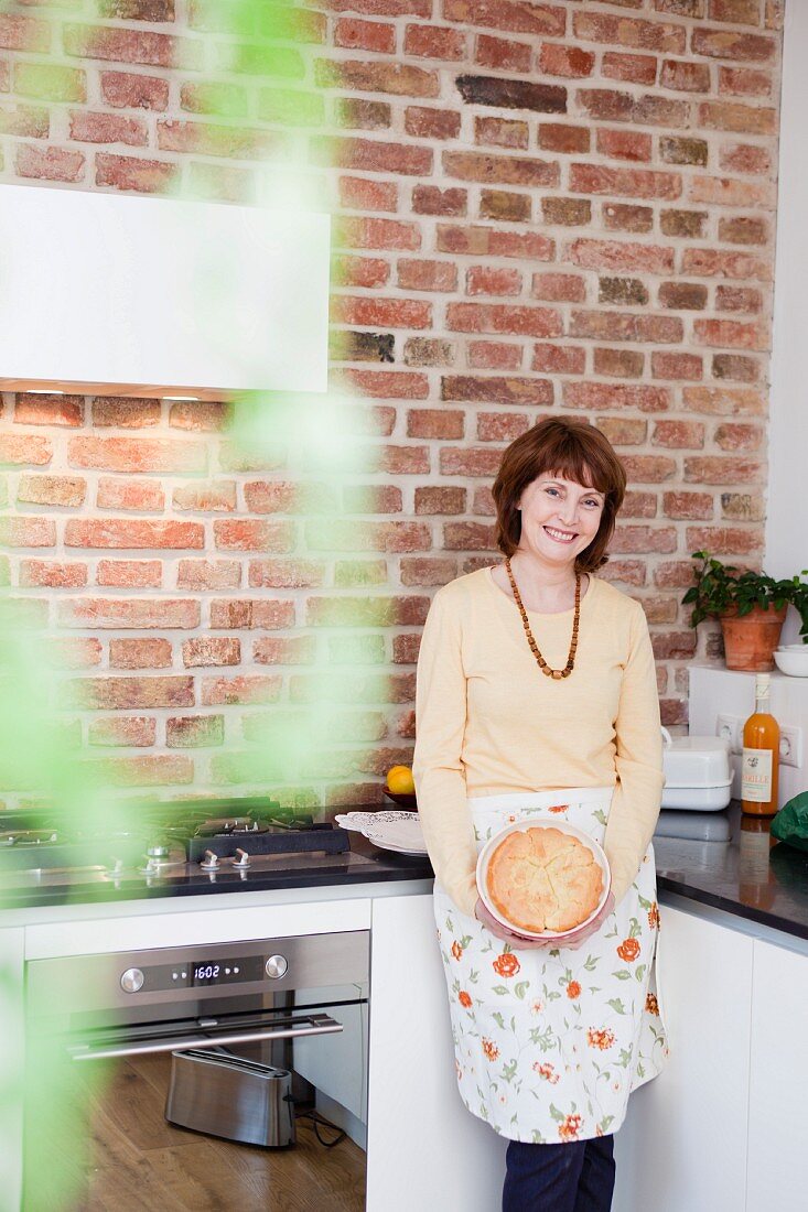 Lächelnde Frau mit Kuchen in der Küche