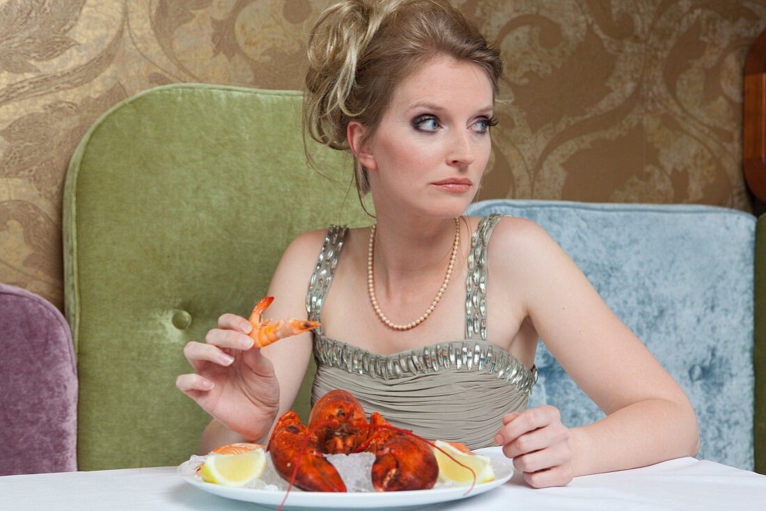 Frau im Abendkleid isst Hummer