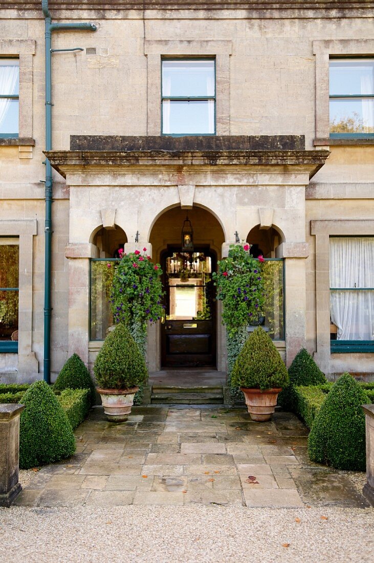 Path lined with clipped box bushes leading to entrance portal of romantic traditional hotel