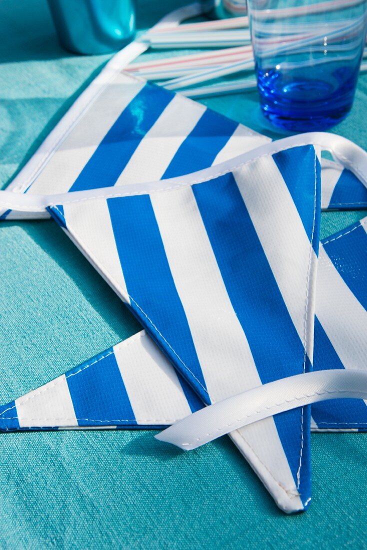 Blue and white striped bunting and drinking glass on blue tablecloth