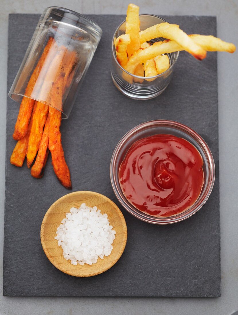 White and Sweet Potato French Fries in Glass Containers with Ketchup and Salt