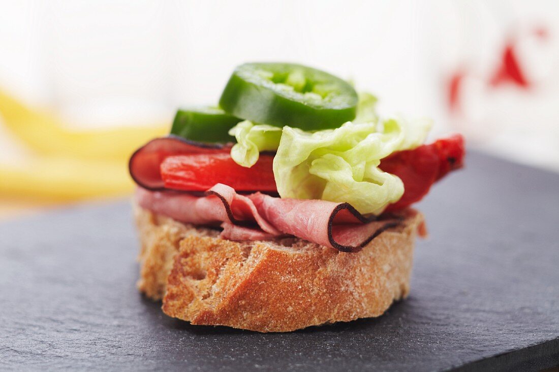 Belegtes Brot mit Schinken, gebratenem Paprika und Jalapenos