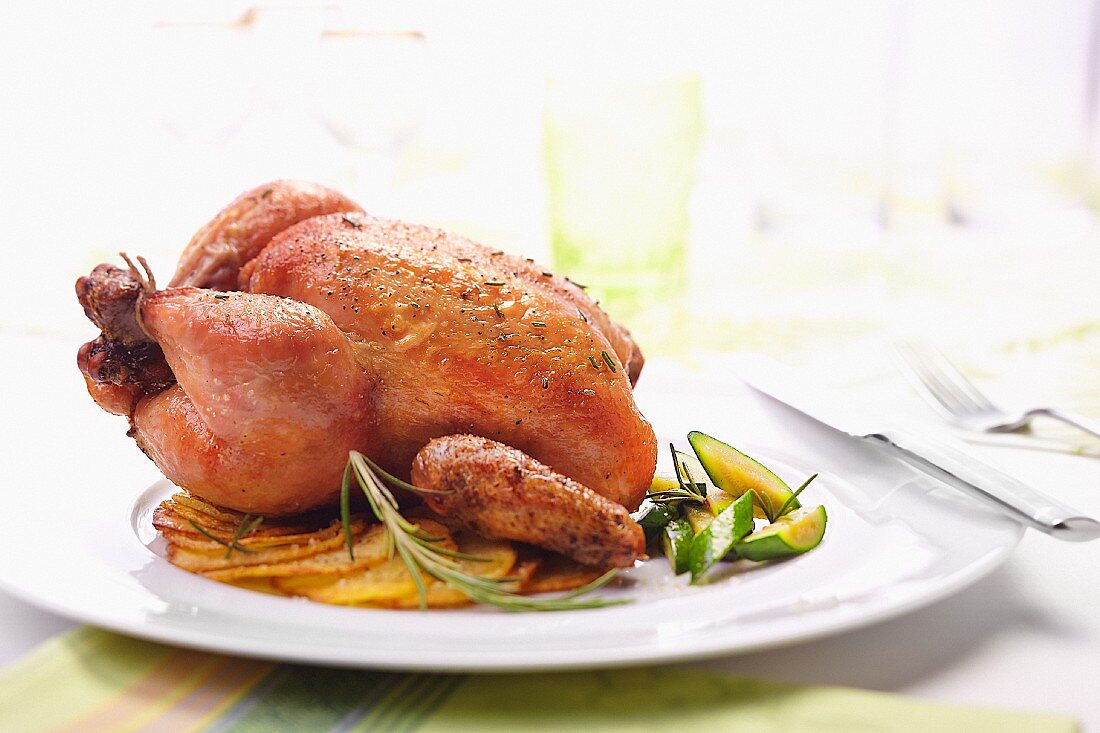 Hähnchen auf einer Platte mit Kartoffelscheiben und Zucchini