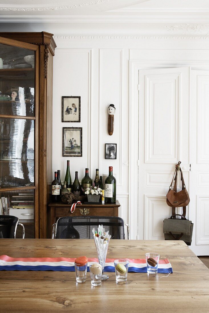 Wooden table with a Tricolor banner, in the background and side table with wine bottles and an antique armoire