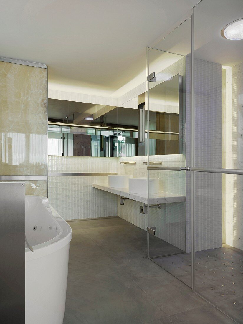 Ein Designerbad mit Glaswand und -tür und einem Spiegelstreifen an der Wand